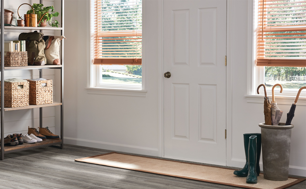 light wood look blinds by front door in entryway with grey wood-look vinyl flooring